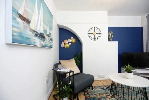 Stylish living room with navy blue accent wall and nautical-themed artwork.