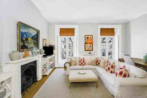 Bright living room with white walls, large windows, and cozy seating area.
