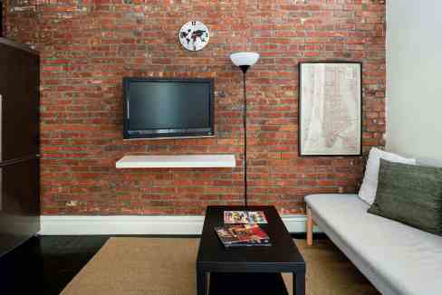 Contemporary living room with brick wall, TV, and cozy sofa.