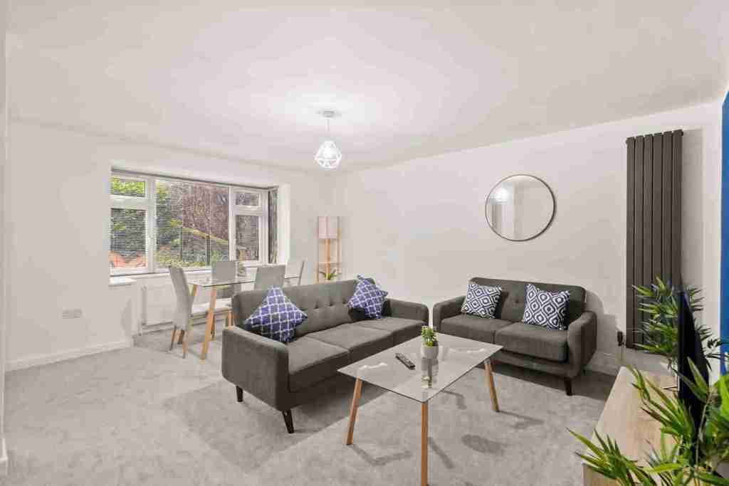Spacious living room with grey sofas, coffee table, and large window.