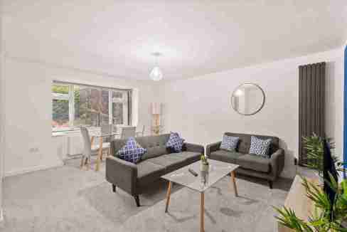 Spacious living room with grey sofas, coffee table, and large window.
