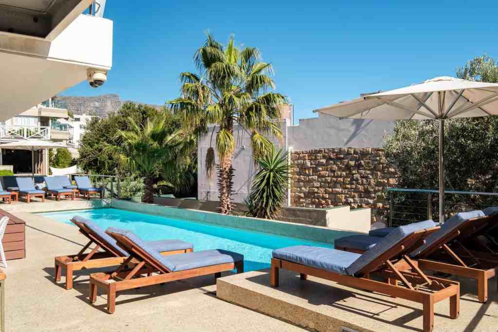 Poolside lounge chairs with umbrellas at a luxury serviced apartment.