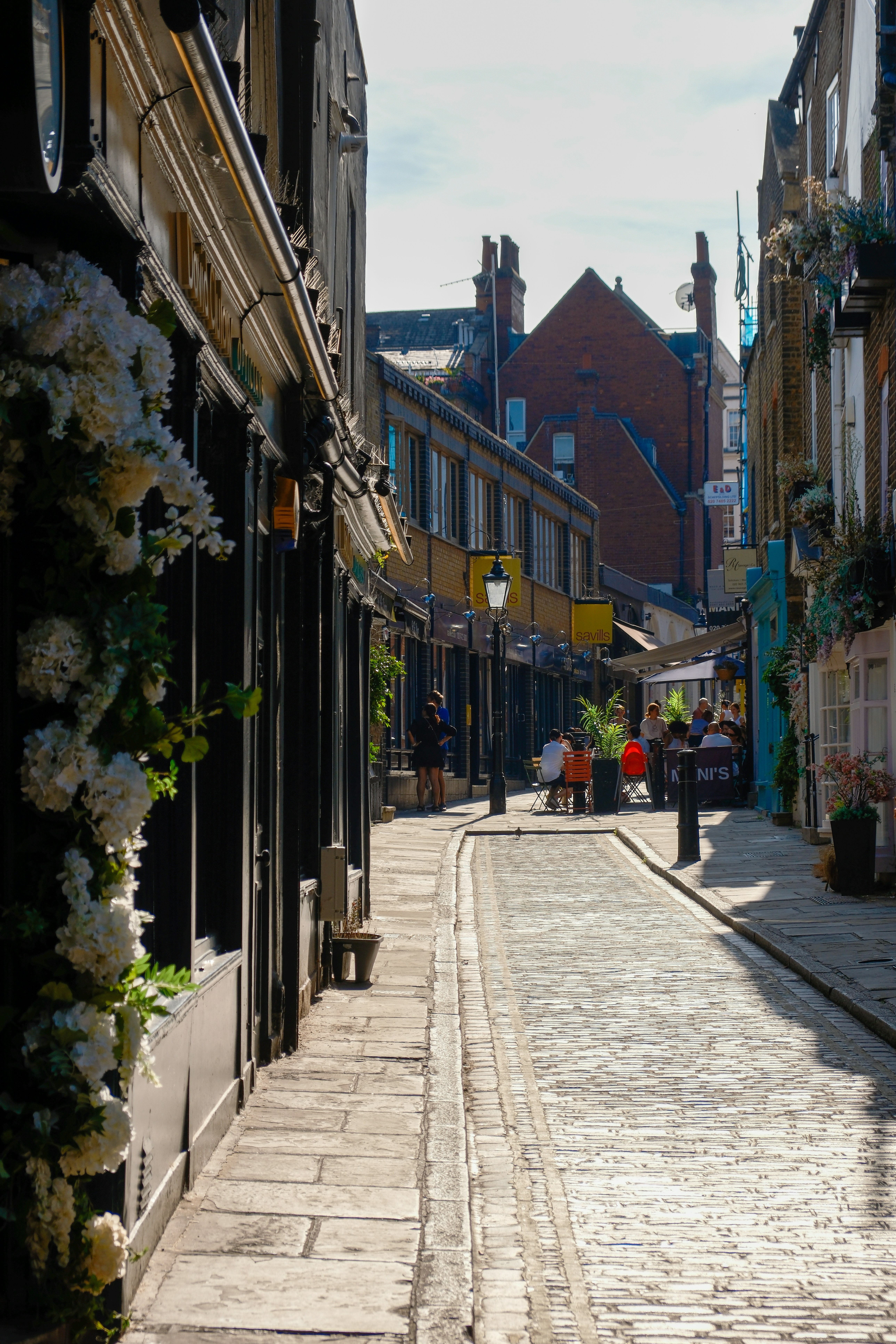 Scenic cobblestone street with shops and pedestrians in Hampstead