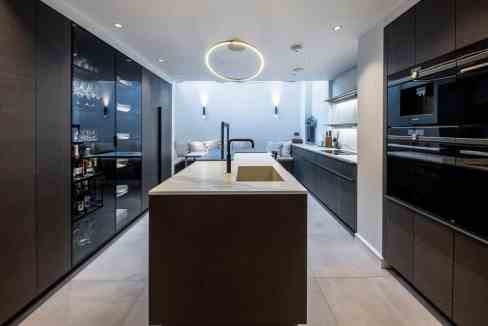 Contemporary kitchen with sleek black cabinetry and central island in Belgravia Emery.