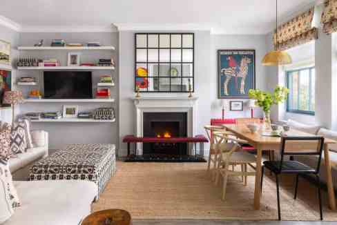 Modern living room with fireplace, bookshelves, and dining area in Knightsbridge Mews House.