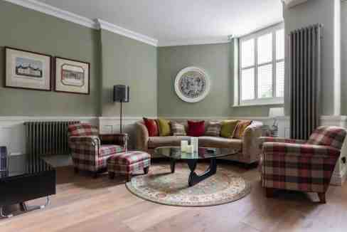 Stylish living room with plaid armchairs and a sofa in Covent Garden apartment.