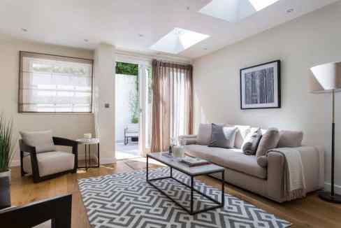 Bright and airy living room with sofa, armchair, and natural light from skylights.