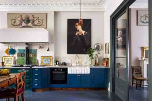 Stylish kitchen with blue cabinets, artwork, and modern decor.