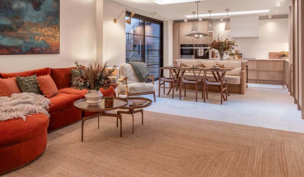 Stylish living room with red sofa, modern decor, and open kitchen in Chelsea townhouse.