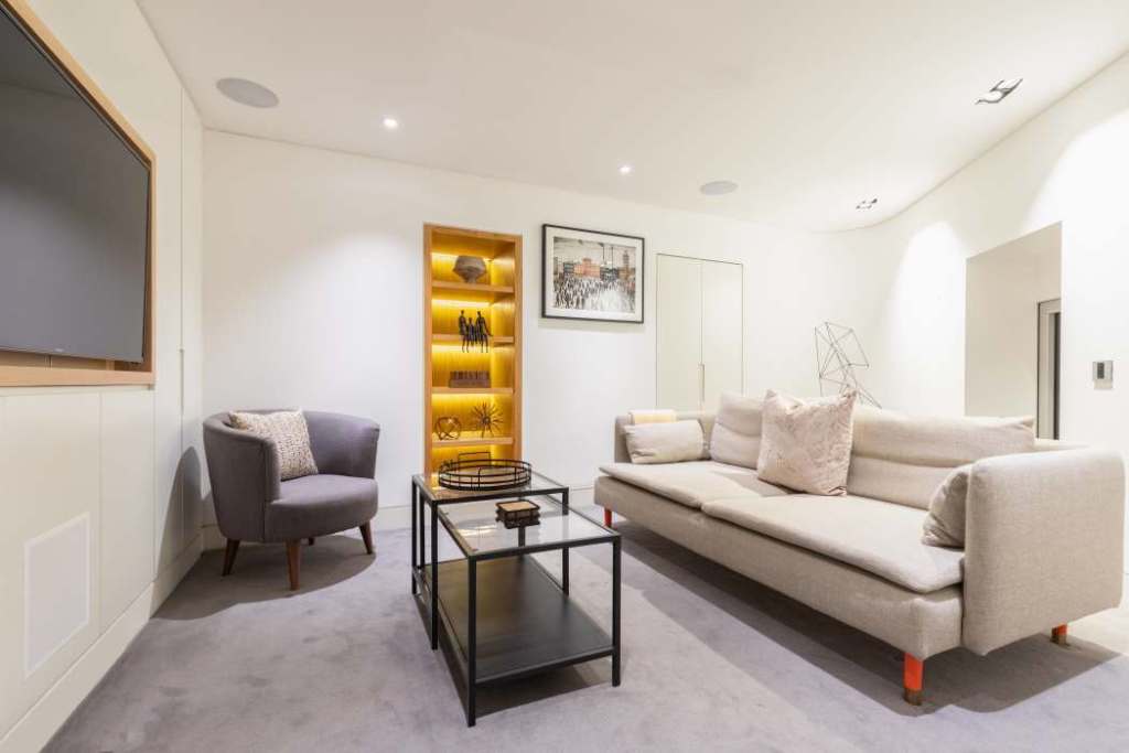 Contemporary living room with sofa, armchair, and decorative shelving.