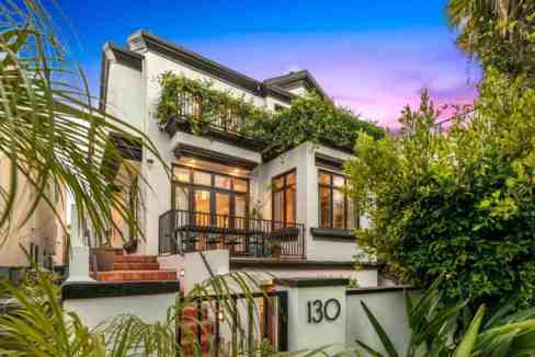 Elegant modern house with lush garden and sunset sky.