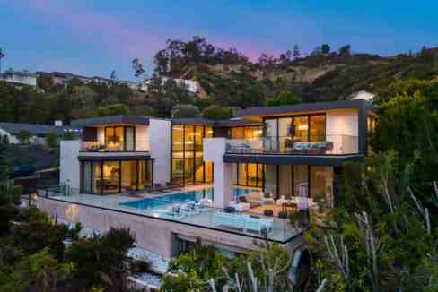 Contemporary villa with infinity pool and hillside views at sunset.