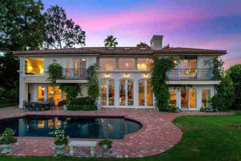 Luxurious estate with pool and lush greenery at sunset.