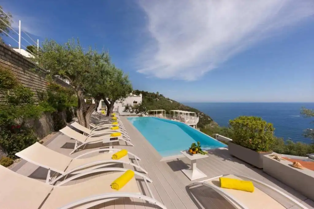 Infinity pool overlooking the ocean with sun loungers and umbrellas.