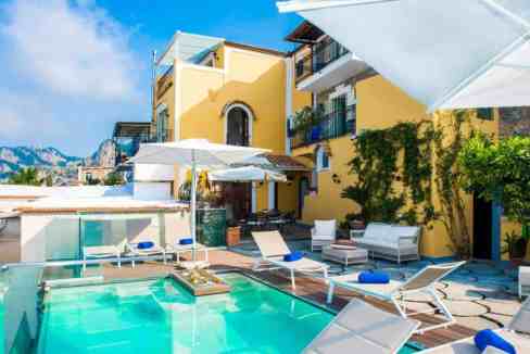 Luxury villa with pool, sun loungers, and mountain backdrop in Italy.