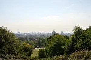 Panoramic view of London skyline from Hampstead with greenery in foreground.
