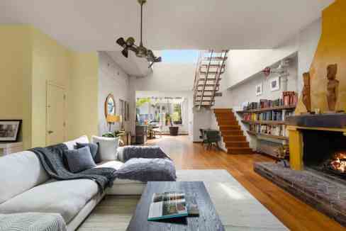 Spacious living room with fireplace, wooden staircase, and large windows.