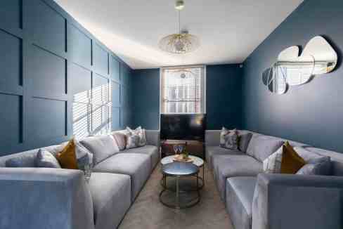 Stylish living room with blue walls, large sofas, and modern decor.
