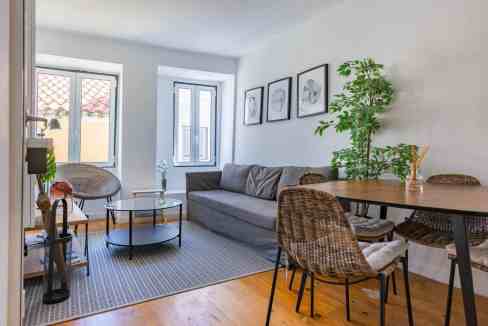 Bright living room with sofa, dining table, and artwork in Alfama.