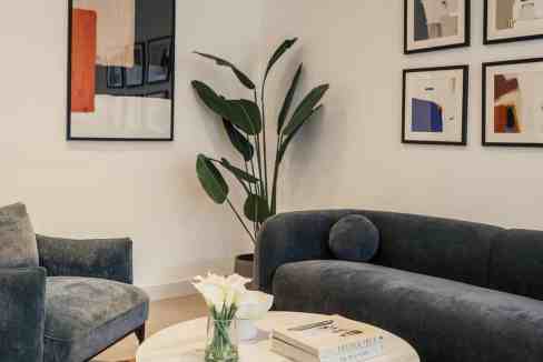 Contemporary living room with abstract art, velvet sofas, and indoor plant.
