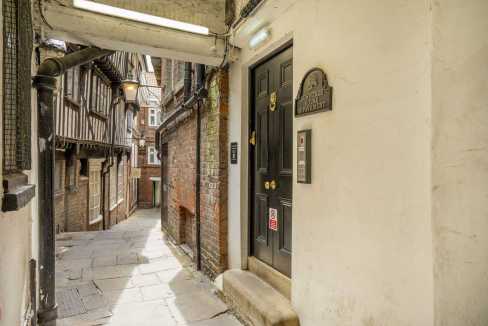 Charming narrow alleyway with brick buildings and a black door in York.