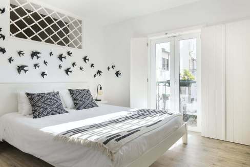 Bright bedroom with white walls, black and white bedding, and artistic bird wall decor.