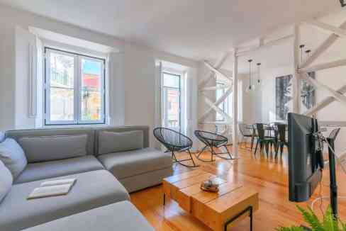 Bright living room with large windows, modern furniture, and wooden flooring in Lisbon.
