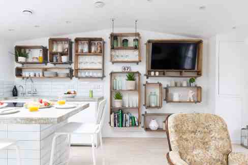 Bright living room with wall-mounted shelves and a flat-screen TV.