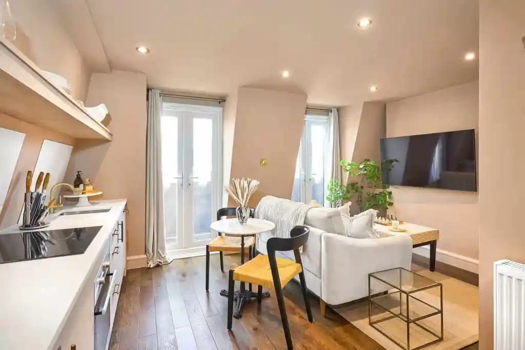 Bright living room with sofa, dining area, and wall-mounted TV in a serviced apartment.