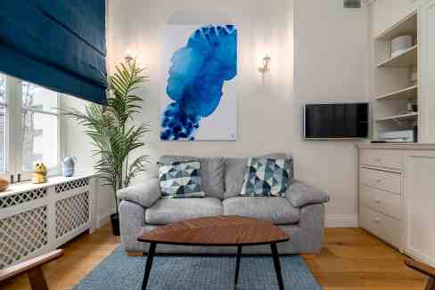 Cozy living room with gray sofa, abstract blue art, and natural light.