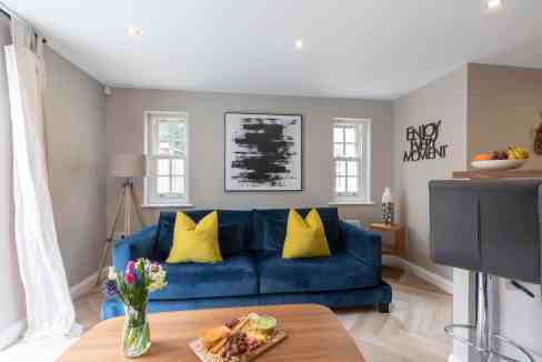 Modern living room with blue sofa and yellow cushions in Cheltenham.