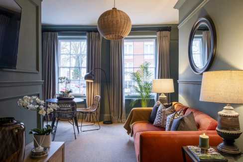 Stylish living room with large windows, cozy sofa, and modern decor.
