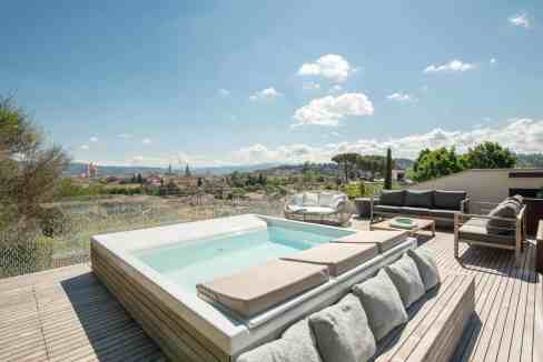 Modern rooftop pool with sun loungers and cityscape view.