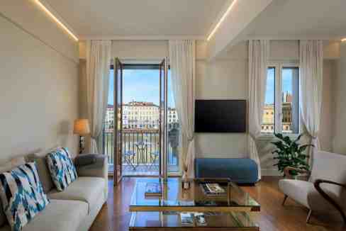 Bright living room with balcony view of Florence river and cityscape.