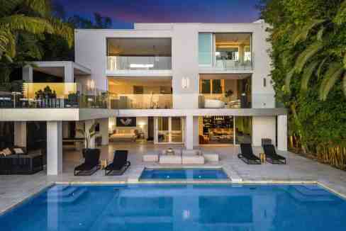Contemporary villa with pool and outdoor lounging area at sunset.