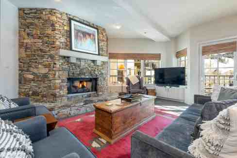 Cozy living room with stone fireplace, large windows, and modern furniture.