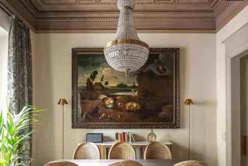 Luxurious dining room with chandelier, antique painting, and vintage furniture.