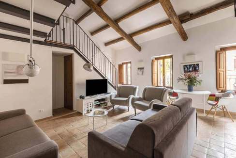 Spacious living room with modern furniture and wooden ceiling beams.