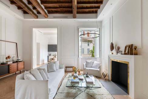 Bright and stylish living room with white furniture and wooden ceiling beams.