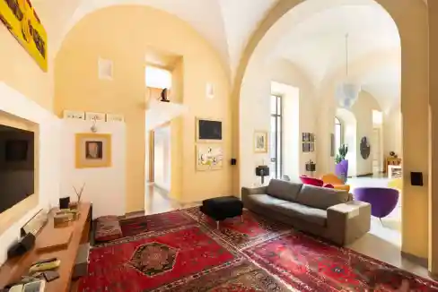 Spacious living room with high ceilings, colorful furniture, and large windows.