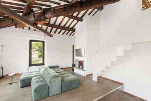 Modern living room with exposed wooden beams and a green sectional sofa.