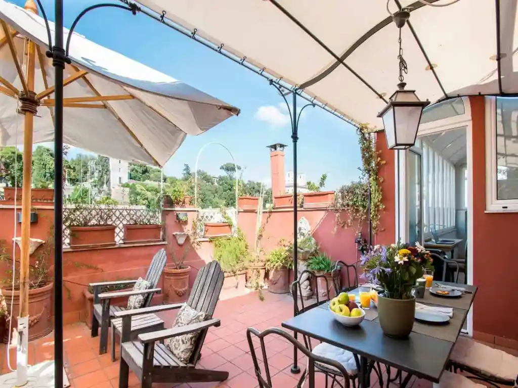 Charming outdoor terrace with seating, umbrellas, and potted plants in a serviced apartment.