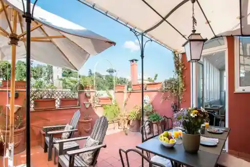 Charming outdoor terrace with seating, umbrellas, and potted plants in a serviced apartment.