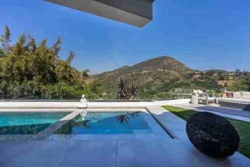 Modern outdoor pool with scenic mountain backdrop and minimalist decor.