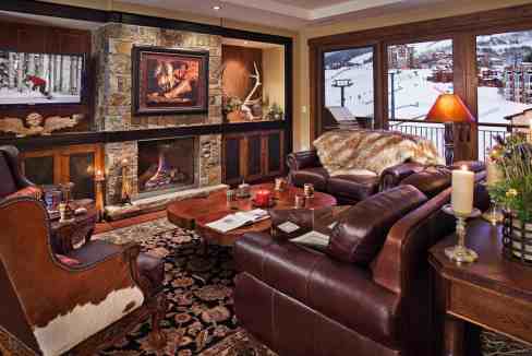 Cozy mountain lodge living room with fireplace and large windows.