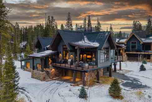 Elegant mountain chalet with large balcony and snow-covered surroundings.
