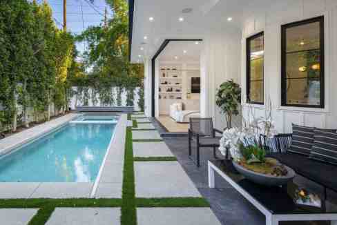 Contemporary outdoor pool area with seating and lush greenery in Beverly Grove.