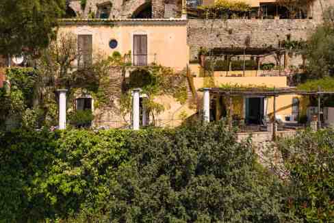 Clifftop villa in Positano with lush garden and colorful exterior walls.