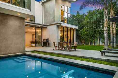 Modern Beverly Hills poolhouse with outdoor dining and pool view.