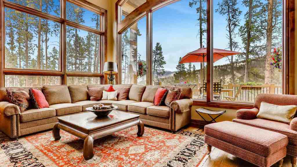 Spacious living room with large windows overlooking forest scenery.